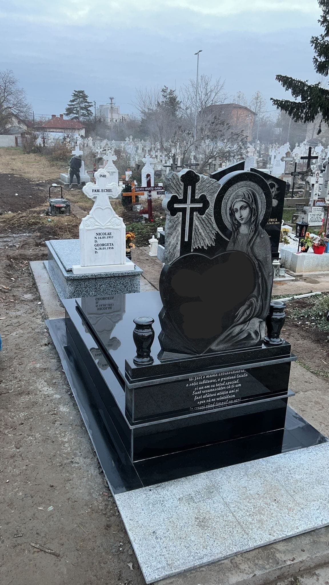 Monument din granit negru cu gravură de înger și inimă, montat pe loc de veci