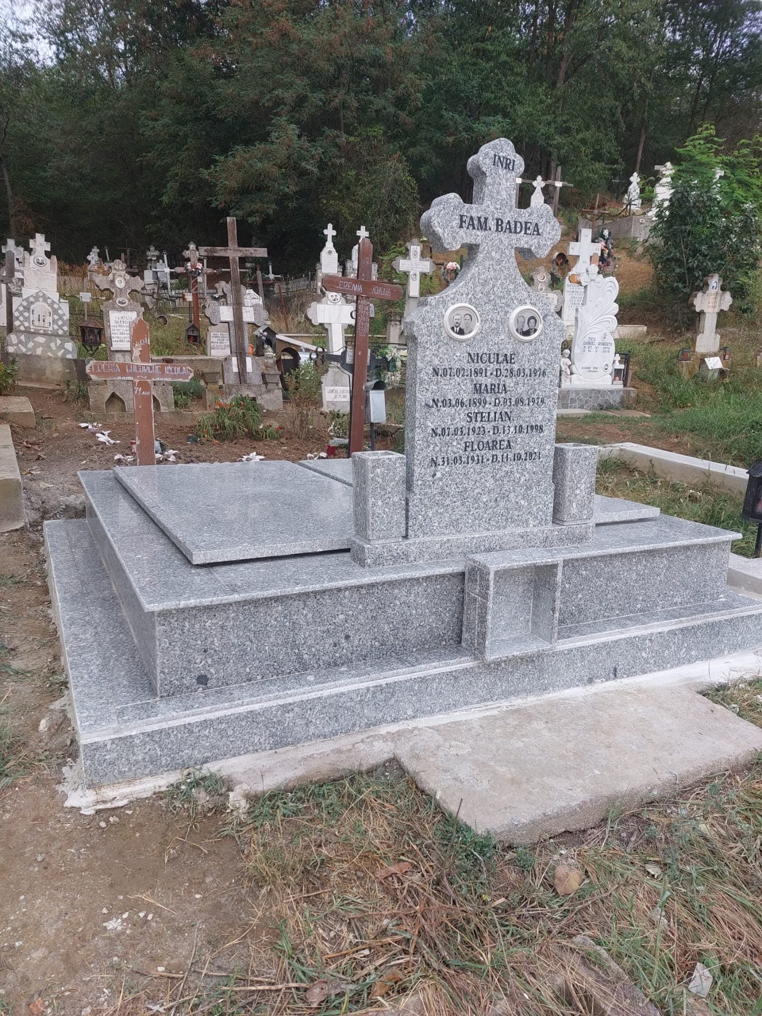 Monument din granit gri cu cruce sculptată și placă gravată de familie